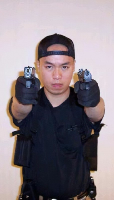 Fotografía de Cho Seung-Hui, mirando fijamente a cámara, con gesto serio y empuñando dos armas de fuego, una en cada mano.